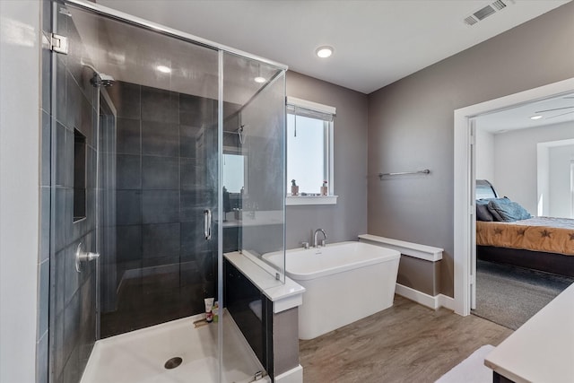 770 Dogberry Ct, Conroe, TX 77304 - bathroom with wood finished floors, a soaking tub, a shower stall, ensuite bath, and recessed lighting