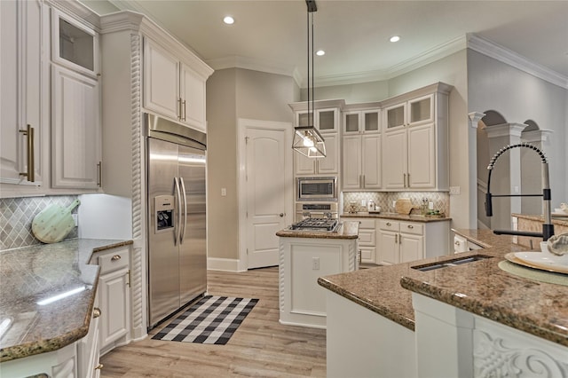 15471 Castlebrook Ct, Montgomery, TX 77316 - kitchen featuring built in appliances, a kitchen island, light wood finished floors, tasteful backsplash, and crown molding