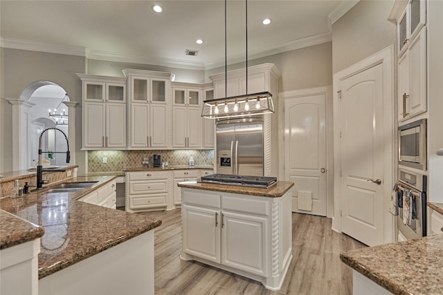 15471 Castlebrook Ct, Montgomery, TX 77316 - kitchen featuring built in appliances, a sink, decorative columns, a kitchen island, and arched walkways