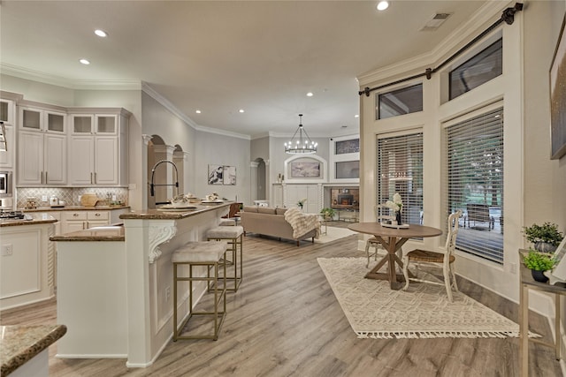 15471 Castlebrook Ct, Montgomery, TX 77316 - kitchen with a kitchen island with sink, recessed lighting, light wood-type flooring, glass insert cabinets, and stone countertops