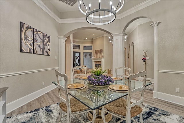 15471 Castlebrook Ct, Montgomery, TX 77316 - dining room with ornate columns, arched walkways, light wood-type flooring, ornamental molding, and a chandelier