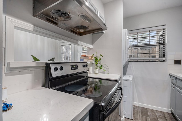 8245 Kingsbrook Rd Unit 139, Houston, TX 77024 - kitchen featuring electric stove, under cabinet range hood, wood finished floors, tasteful backsplash, and light countertops