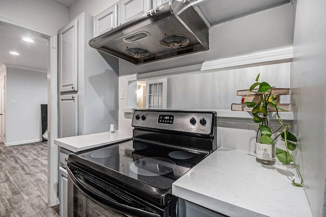 8245 Kingsbrook Rd Unit 139, Houston, TX 77024 - kitchen featuring electric stove, under cabinet range hood, light countertops, light wood-style flooring, and crown molding