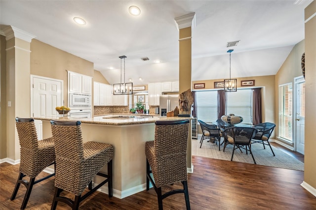 kitchen with lofted ceiling, white appliances, a chandelier, plenty of natural light, and dark wood finished floors