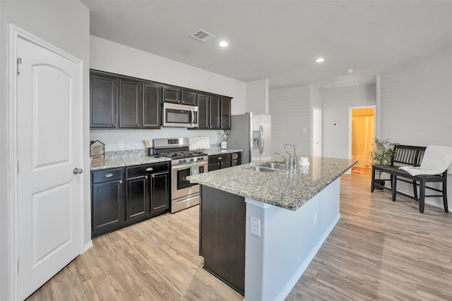 11355 Dawn Beach Ln, Conroe, TX 77304 - kitchen with appliances with stainless steel finishes, a sink, an island with sink, light wood-style flooring, and recessed lighting