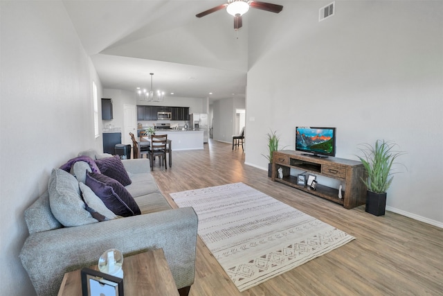 11355 Dawn Beach Ln, Conroe, TX 77304 - living area with a chandelier, light wood-type flooring, a ceiling fan, baseboards, and vaulted ceiling