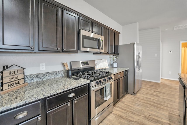 11355 Dawn Beach Ln, Conroe, TX 77304 - kitchen featuring appliances with stainless steel finishes, light wood-style flooring, light stone countertops, and baseboards