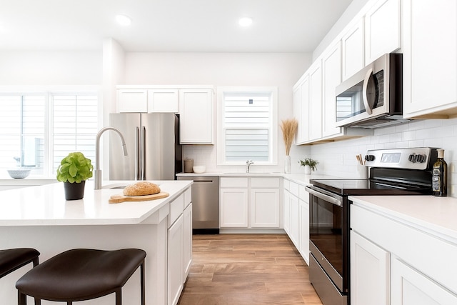 16912 Kempwood, Montgomery, TX 77316 - kitchen featuring appliances with stainless steel finishes, a breakfast bar area, light countertops, tasteful backsplash, and light wood-style floors