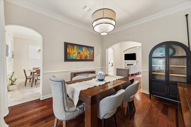 14402 Basalt Ln, Houston, TX 77077 - dining room featuring arched walkways, ornamental molding, dark wood-type flooring, and baseboards