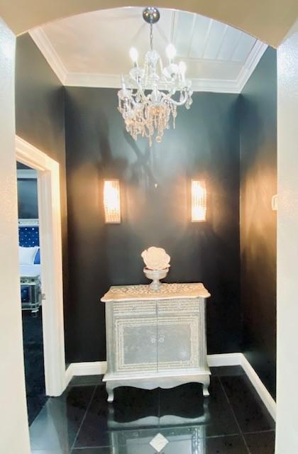 detailed view of ornamental molding, a chandelier, and baseboards