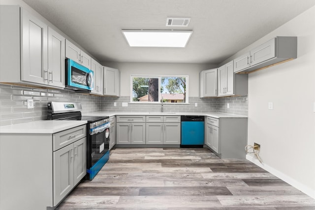 4434 Falcon Meadow Dr, Katy, TX 77449 - kitchen with stainless steel appliances, a sink, light wood-style floors, tasteful backsplash, and light countertops