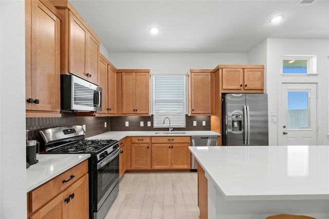 21106 Garden Palm Dr, Cypress, TX 77433 - kitchen with appliances with stainless steel finishes, a sink, light countertops, decorative backsplash, and light wood-style flooring
