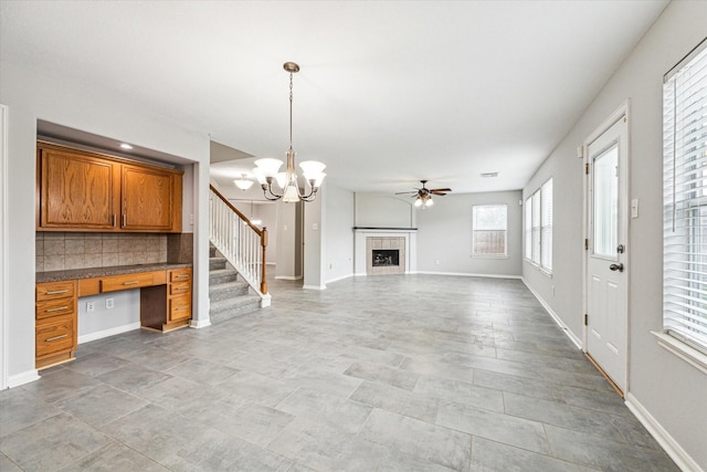 1056 Inverness Cv, Dickinson, TX 77539 - unfurnished living room featuring a ceiling fan, a tile fireplace, a chandelier, and baseboards