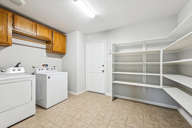 1056 Inverness Cv, Dickinson, TX 77539 - washroom featuring cabinet space, washer and clothes dryer, a textured ceiling, light tile patterned floors, and baseboards