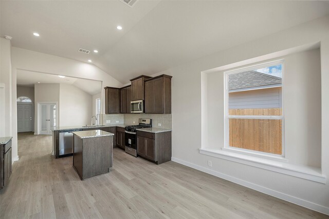 658 Cherry Tree Dr, La Marque, TX 77568 - kitchen with appliances with stainless steel finishes, a center island, dark brown cabinets, decorative backsplash, and a peninsula