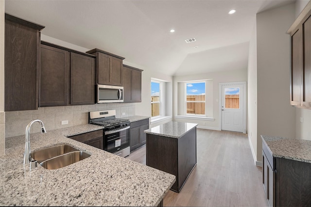 658 Cherry Tree Dr, La Marque, TX 77568 - kitchen with appliances with stainless steel finishes, a sink, a center island, dark brown cabinets, and backsplash