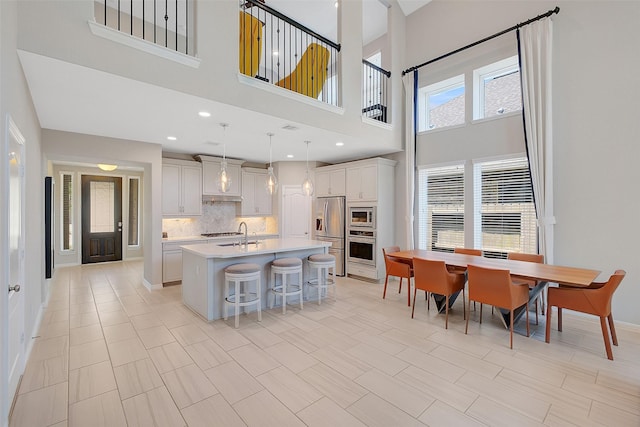 6323 Grand Summit Ct, Katy, TX 77494 - kitchen with appliances with stainless steel finishes, light countertops, an island with sink, decorative backsplash, and a kitchen breakfast bar