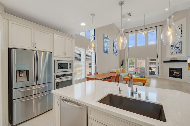 6323 Grand Summit Ct, Katy, TX 77494 - kitchen featuring stainless steel appliances, a sink, hanging light fixtures, light stone countertops, and white cabinets