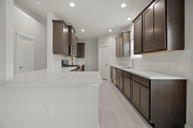 666 Cherry Tree Dr, La Marque, TX 77568 - kitchen with appliances with stainless steel finishes, a sink, dark brown cabinetry, a peninsula, and recessed lighting