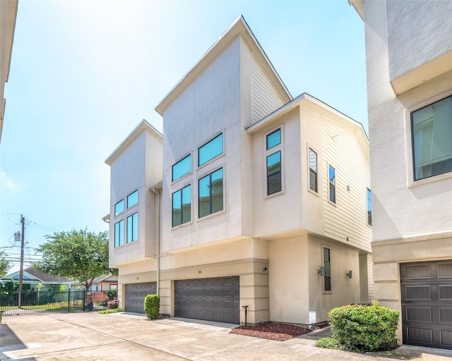 34 N Hutcheson St, Houston, TX 77003 - view of front of house with stucco siding, fence, an attached garage, and concrete driveway