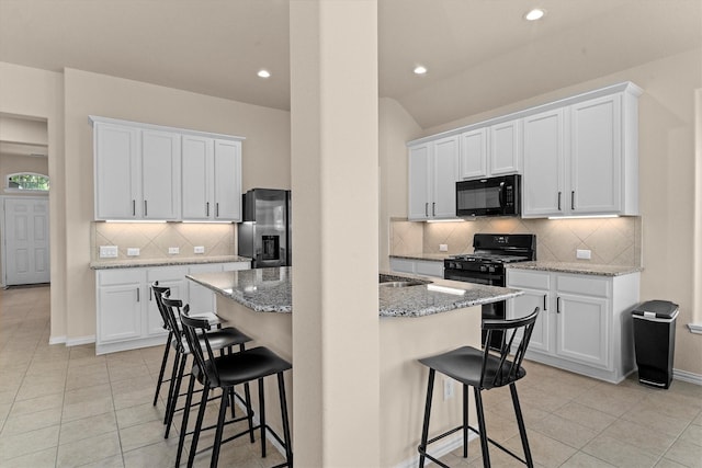 635 W Linnwood Dr, Woodbranch, TX 77357 - kitchen with black appliances, light tile patterned floors, a kitchen breakfast bar, backsplash, and recessed lighting