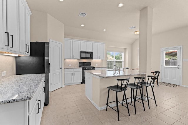 635 W Linnwood Dr, Woodbranch, TX 77357 - kitchen with black appliances, a sink, light tile patterned floors, backsplash, and white cabinetry