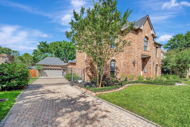 view of front of home featuring brick siding, decorative driveway, and a gate