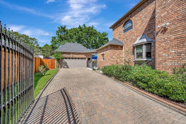 view of home's exterior with brick siding, fence, driveway, and an attached garage
