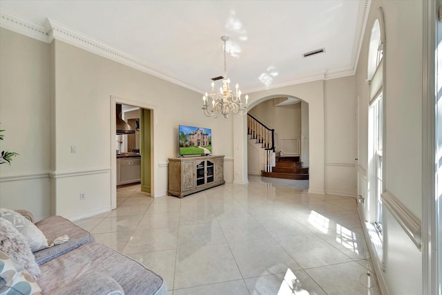 living room with arched walkways, ornamental molding, a chandelier, stairs, and baseboards