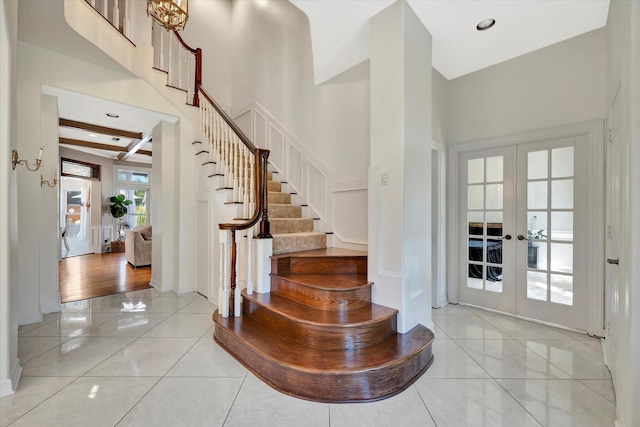 foyer with french doors, stairs, light tile patterned flooring, a high ceiling, and baseboards
