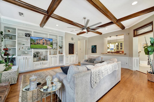 living room with coffered ceiling, beamed ceiling, ceiling fan, light wood finished floors, and ornamental molding