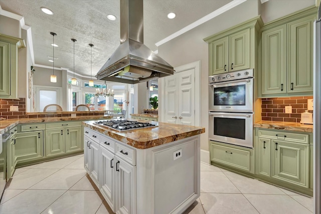kitchen featuring green cabinetry, appliances with stainless steel finishes, light tile patterned floors, island range hood, and decorative backsplash