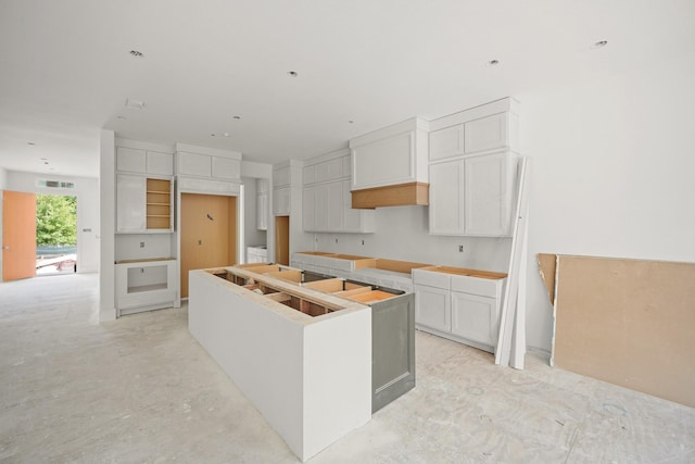 5223 Mimosa Dr, Bellaire, TX 77401 - kitchen featuring a center island, white cabinets, and concrete flooring