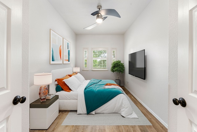 bedroom featuring light wood-style flooring, a ceiling fan, and baseboards