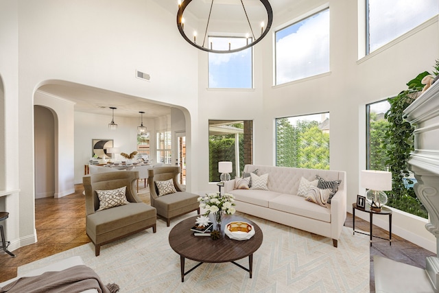 living area featuring arched walkways, healthy amount of natural light, and a high ceiling