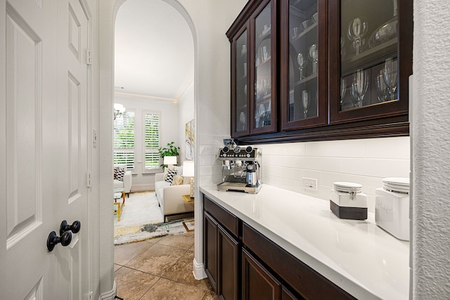 bar with ornamental molding, arched walkways, and tasteful backsplash