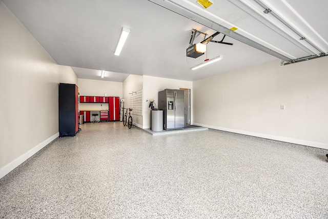 garage featuring stainless steel fridge with ice dispenser, a garage door opener, and baseboards
