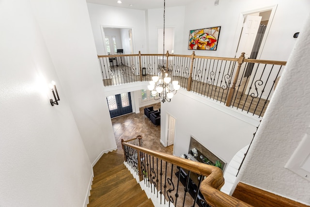 staircase with wood finished floors, a chandelier, a towering ceiling, baseboards, and recessed lighting