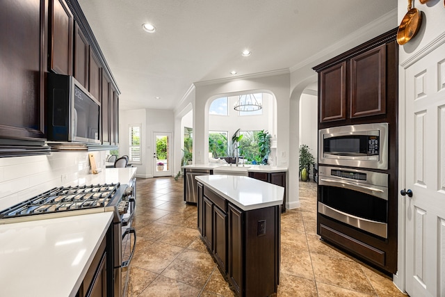 kitchen featuring stainless steel appliances, backsplash, baseboards, light countertops, and dark brown cabinetry