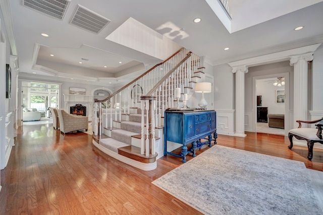 206 Greenbriar Ave, Friendswood, TX 77546 - stairs featuring decorative columns, a lit fireplace, wood finished floors, wainscoting, and a raised ceiling