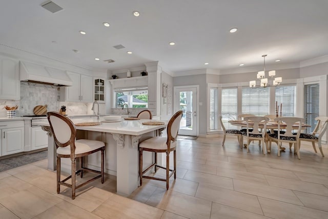 206 Greenbriar Ave, Friendswood, TX 77546 - kitchen featuring custom exhaust hood, a chandelier, a breakfast bar, tasteful backsplash, and light countertops