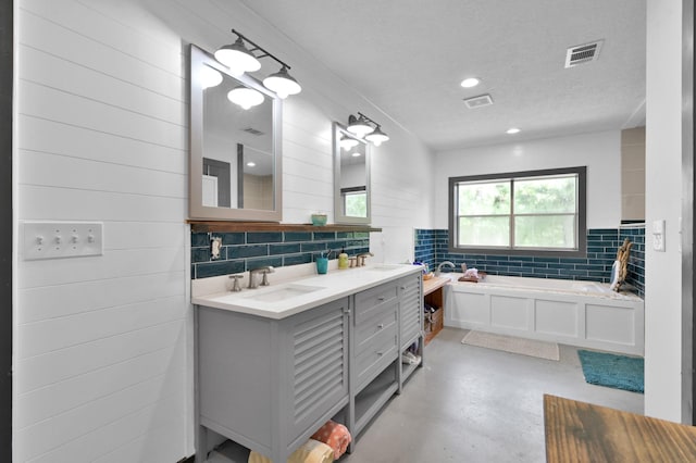 315 Cessna Rd, Trinity, TX 75862 - bathroom featuring concrete flooring, a bath, double vanity, backsplash, and a textured ceiling