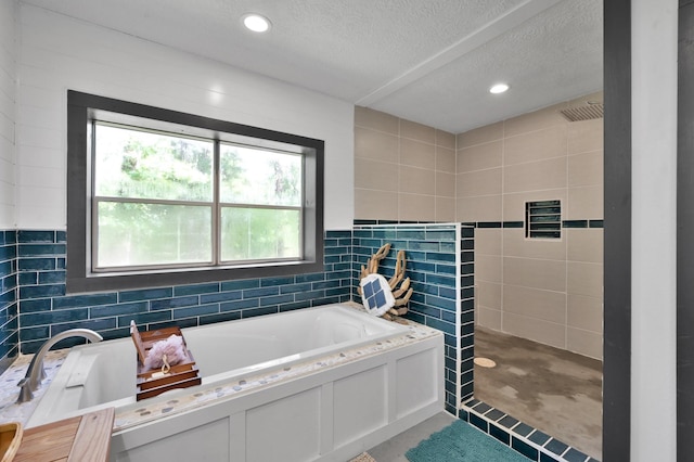 315 Cessna Rd, Trinity, TX 75862 - bathroom featuring a bath, tiled shower, a textured ceiling, recessed lighting, and tile walls