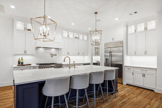 319 E 26th St, Houston, TX 77008 - kitchen with a chandelier, appliances with stainless steel finishes, a sink, an island with sink, and white cabinets