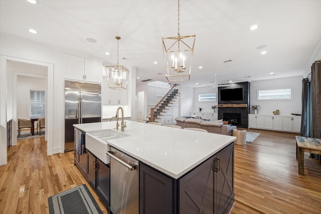 319 E 26th St, Houston, TX 77008 - kitchen featuring a sink, appliances with stainless steel finishes, a chandelier, a large fireplace, and white cabinets