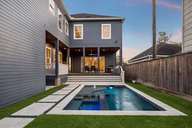 319 E 26th St, Houston, TX 77008 - back of property at dusk featuring an in-ground hot tub, a fenced backyard, and a wooden deck