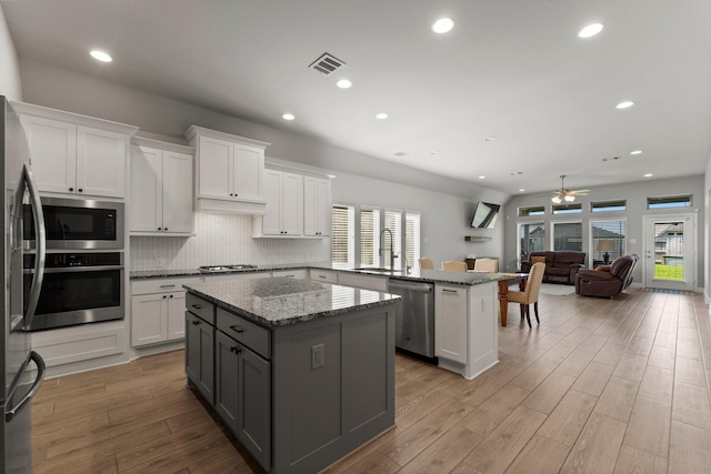 19419 Filly Chase Ct, Tomball, TX 77377 - kitchen with stainless steel appliances, a peninsula, a kitchen island, a ceiling fan, and wood finished floors