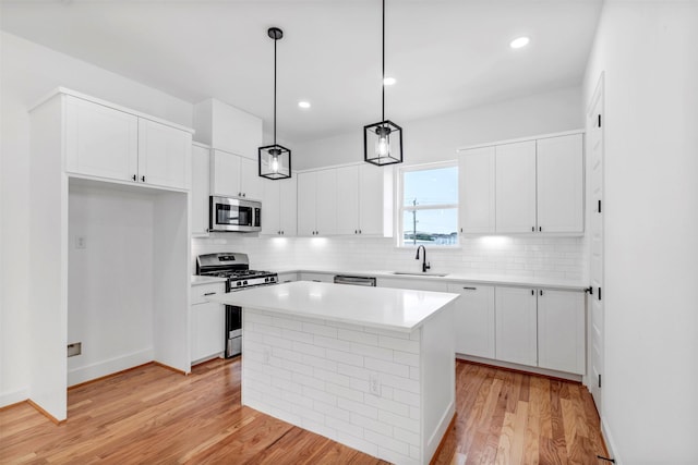 1232 E 23rd St, Houston, TX 77009 - kitchen featuring stainless steel appliances, a sink, light wood-style floors, backsplash, and white cabinets