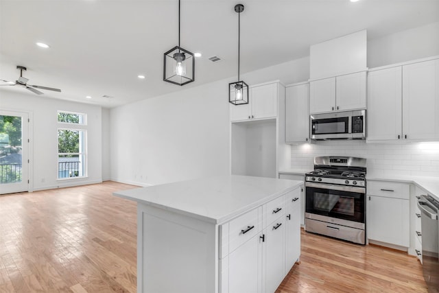 1232 E 23rd St, Houston, TX 77009 - kitchen featuring appliances with stainless steel finishes, a ceiling fan, backsplash, light wood-style floors, and open floor plan