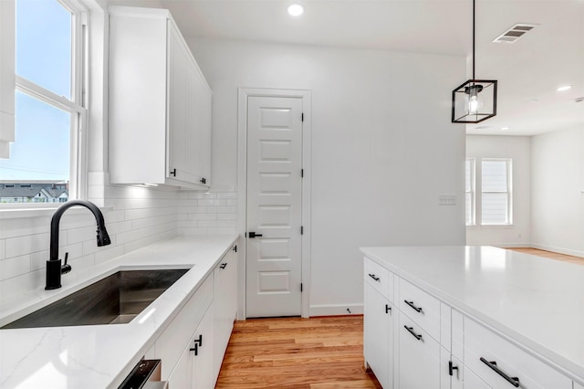 1232 E 23rd St, Houston, TX 77009 - kitchen with a sink, light wood-style floors, backsplash, white cabinets, and recessed lighting